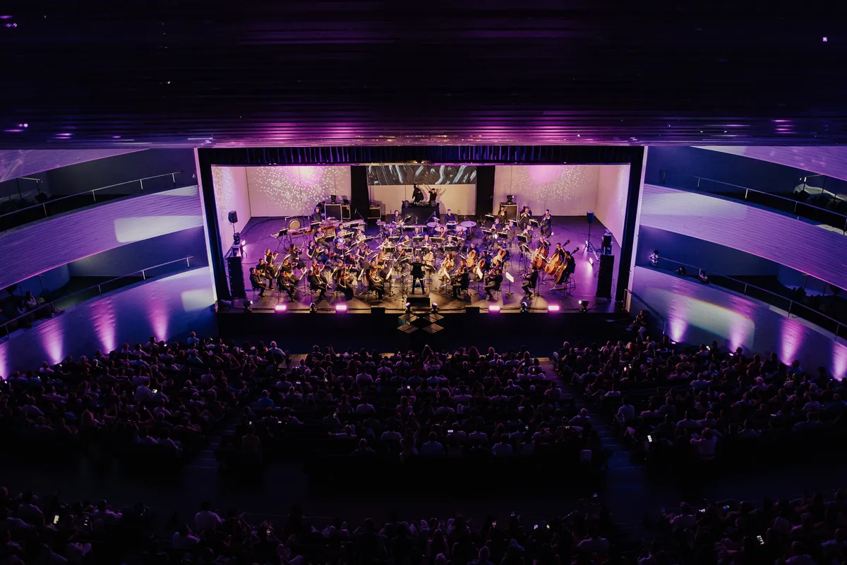 Vista general de un auditorio lleno con luz violeta